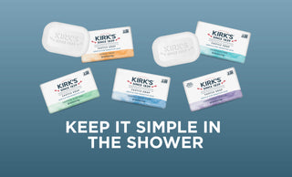 Six Kirk’s Castile soap bars in various colors are arranged above the text “KEEP IT SIMPLE IN THE SHOWER” on a blue gradient background.
